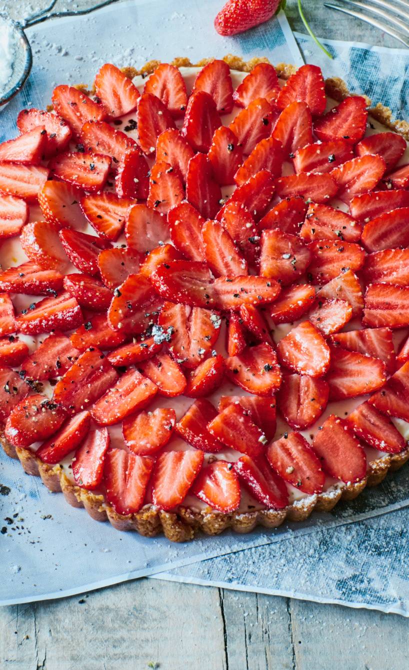 Runder italienischer Erdbeerkuchen mit frischen Erdbeeren und Ziegenfrischkäse-Sahne-Füllung auf einer Kuchenplatte