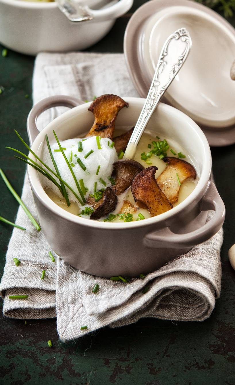 Kartoffelsuppe mit Einlage aus gebratenen Kräuterseitlingen und Topping aus Milchschaum in einem Kochtopf