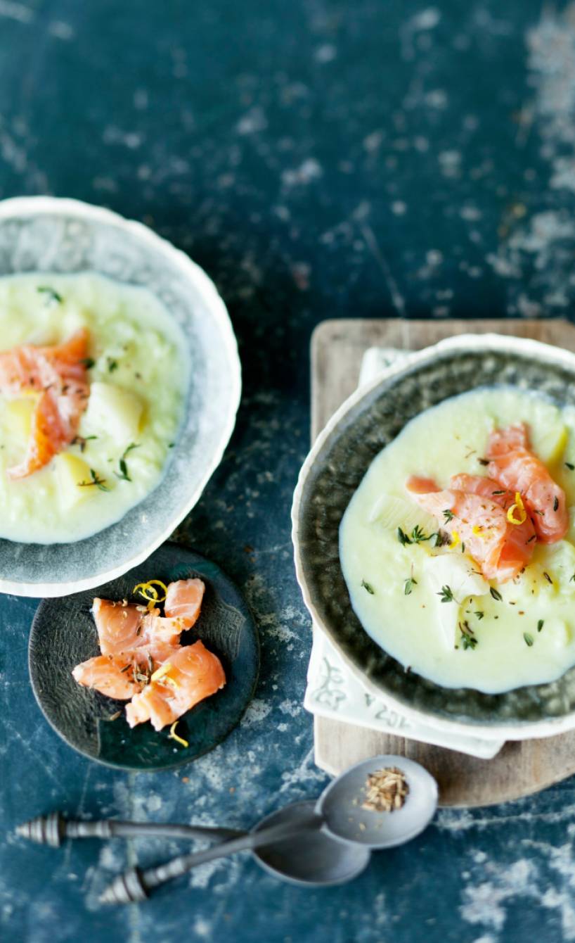 Blumenkohlsuppe mit Fenchel in zwei Schüsseln getoppt mit Räucherlachs und Kräutern auf einem Tisch