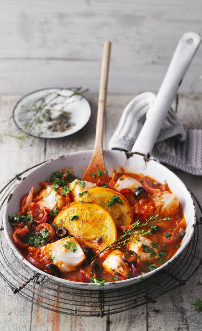 Sizilianische Fischpfanne mit Kapern, Oliven und Orangen auf einem Tisch