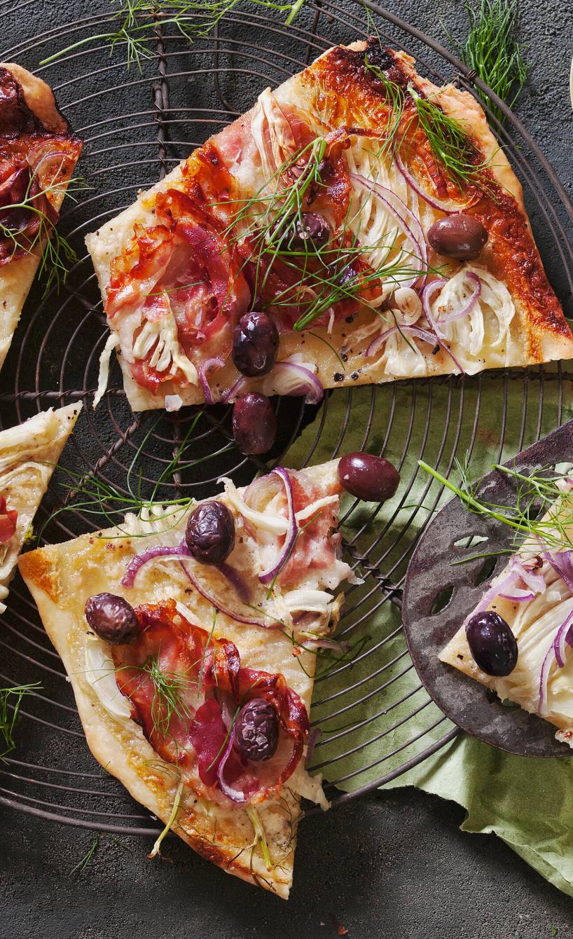 Flammkuchen mit Fenchel und Pancetta in Teile geschnitten auf einem Küchengitter
