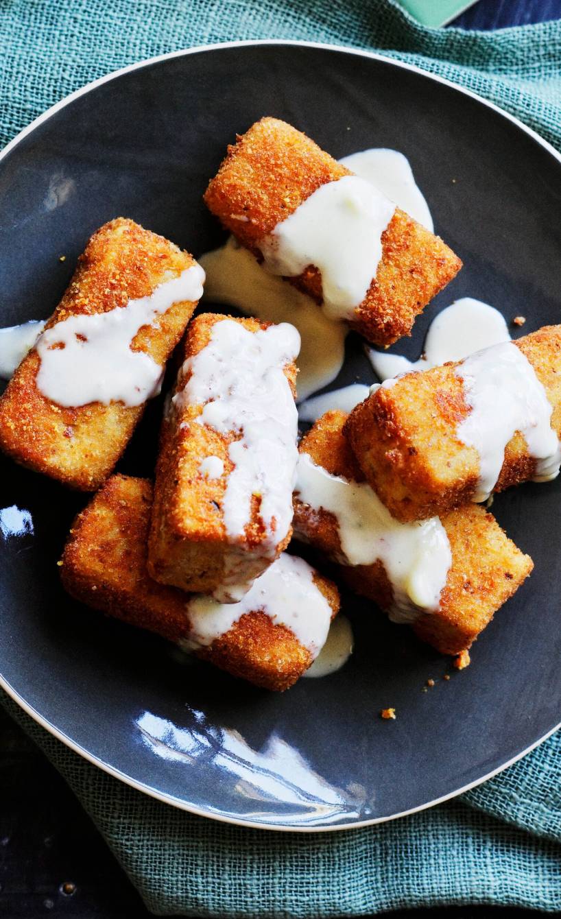 Frittierte Polentasticks in einem tiefen Teller übergossen mit Gorgonzolasoße