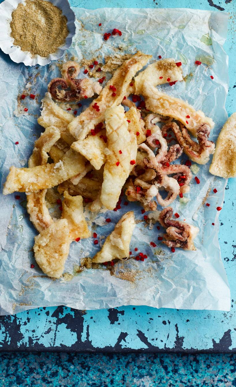 Frittierter Tintenfisch auf einer rechteckigen Platte, daneben Dip