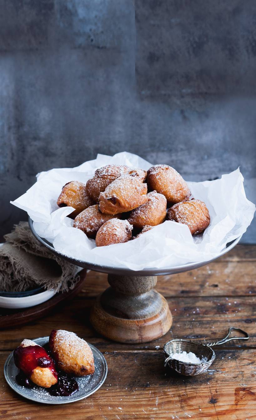 Frittierte Löffel-Krapfen mit Rosinen und Rum angerichtet auf einer Servierplatte