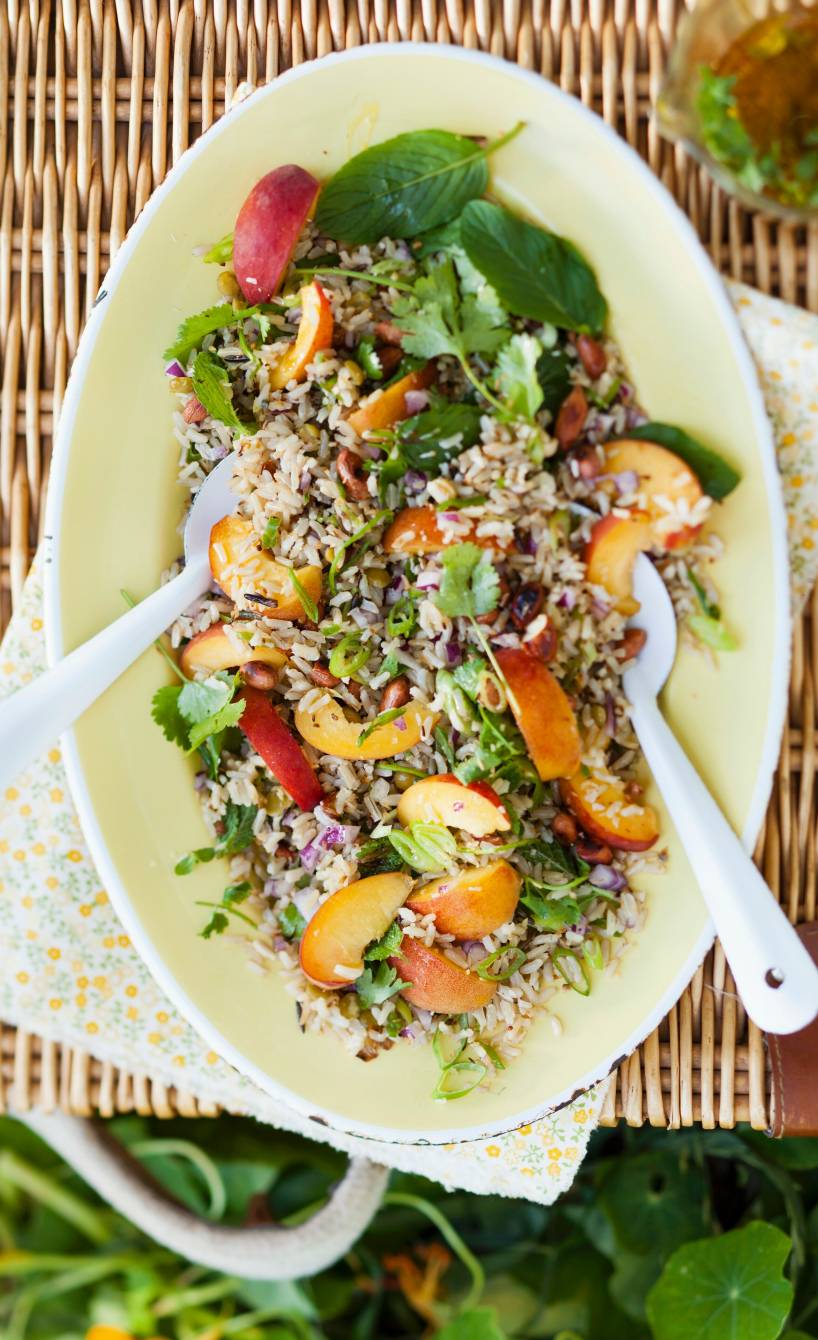 Reissalat auf einem Teller garniert mit Nektarinenspalten und Erdnusskernen