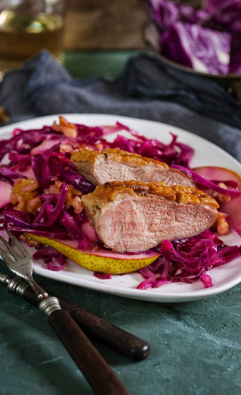 Gebratene Entenbrust in Scheiben auf einem Teller mit Birnen-Rotkohlsalat