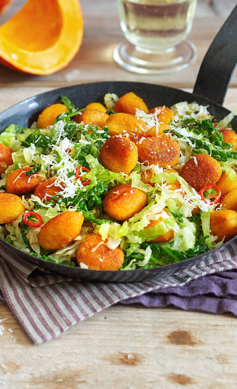 Gebratene Kürbisgnocchi mit Wirsing in einer Pfanne auf einem Tisch