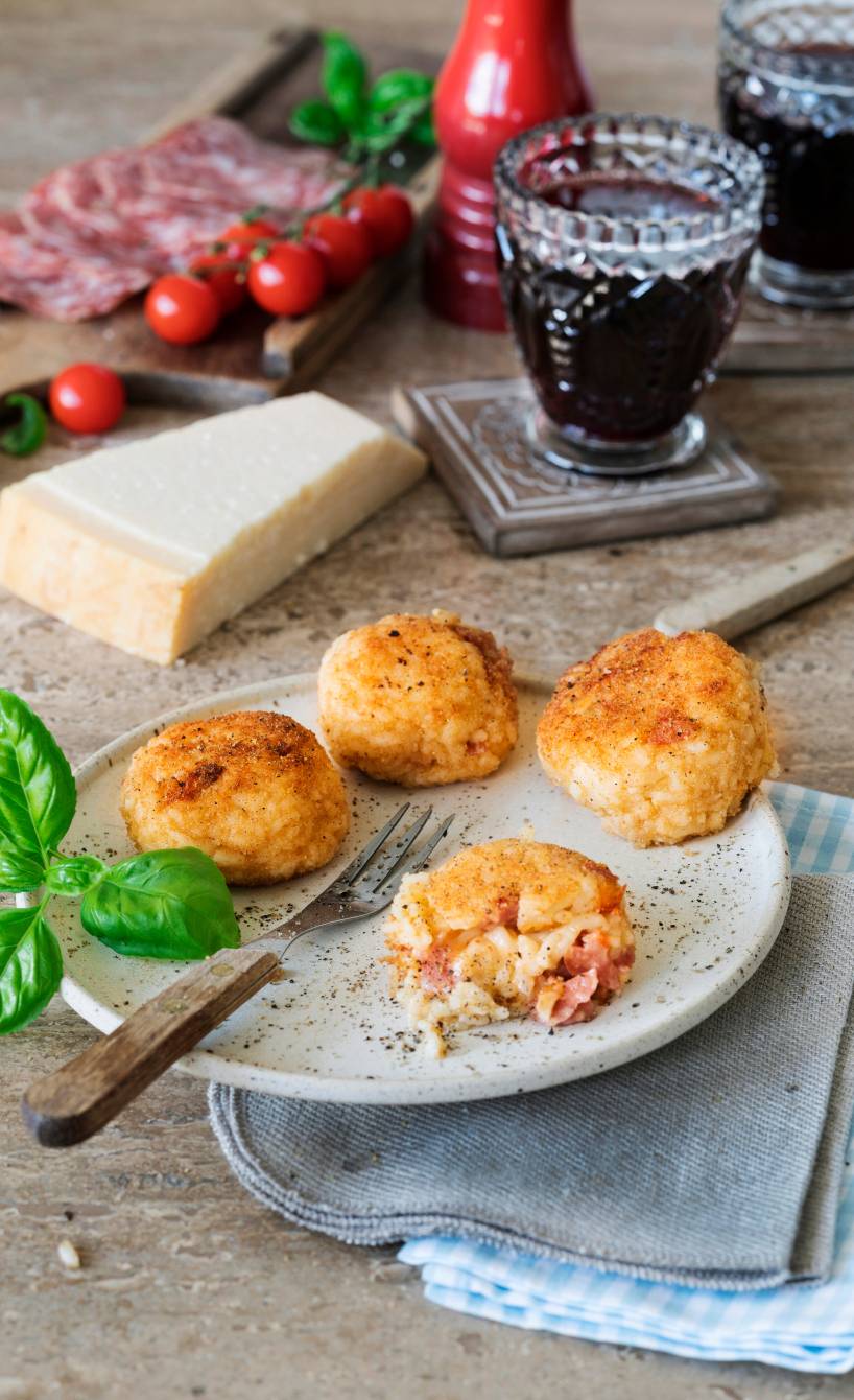 Gebratene Reisbällchen mit Tomaten-Salami-Füllung auf einem Teller