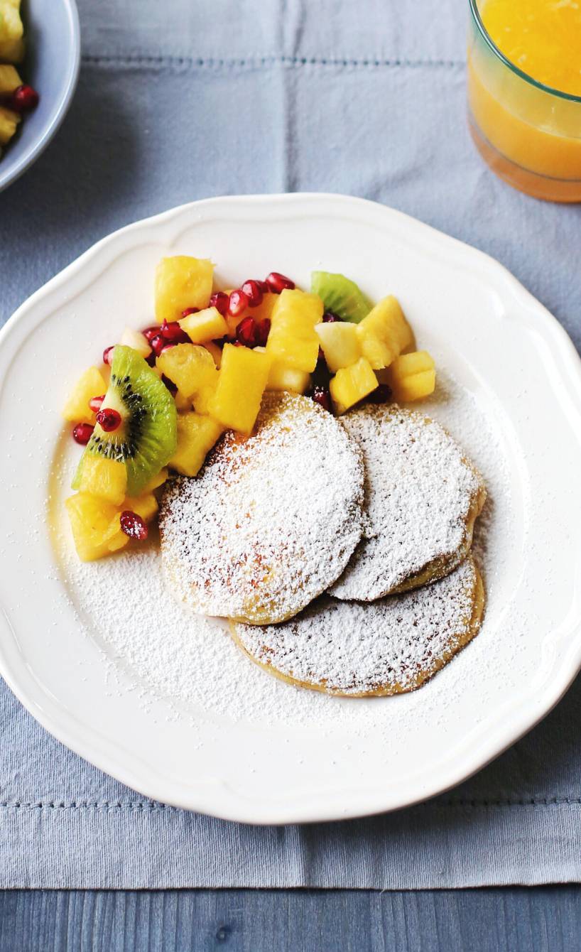 Ricottataler wie Pancakes angerichtet mit Obstsalat auf mehreren Tellern