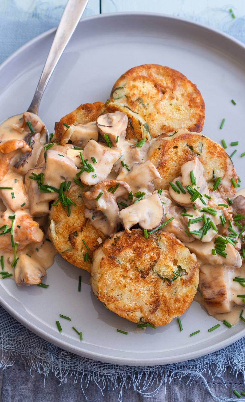 Gebratene Serviettenknödel in Scheiben angerichtet mit Pilzragout auf einem Teller