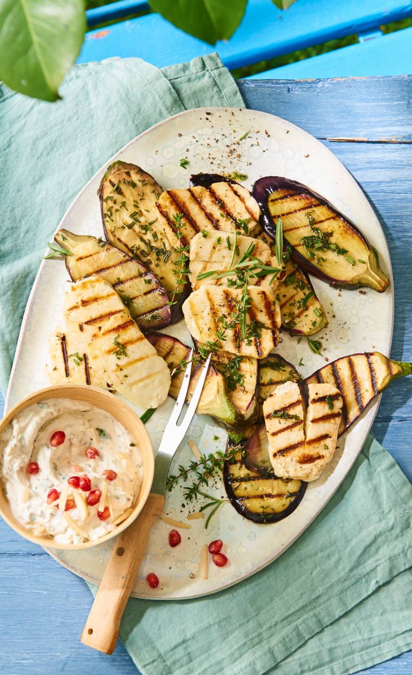 Gegrillte Aubergine und gegrillter Halloumi auf eine Teller, daneben Granatapfel-Quark-Dip in einem Schälchen
