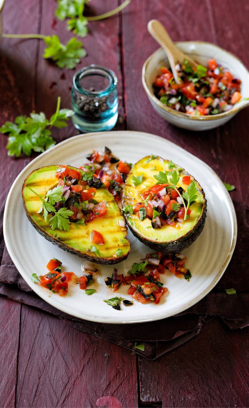 Zwei Gegrillte Avocadohälften mit Tomatensalsa getoppt auf einem Teller