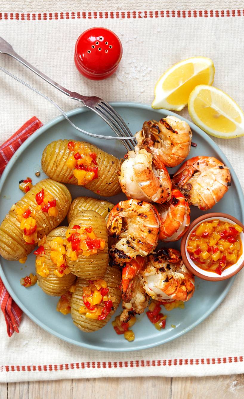 Gegrillte Riesengarnelen und Fächerkartoffeln auf einem Teller getoppt mit Paprika-Mango-Chutney