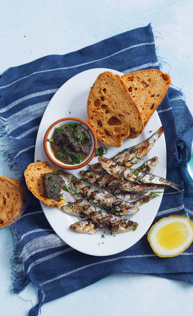 Gegrillte Sardinen nach italienischer Art, daneben mit Tomaten-Ciabatta und Olivencreme auf einem Teller