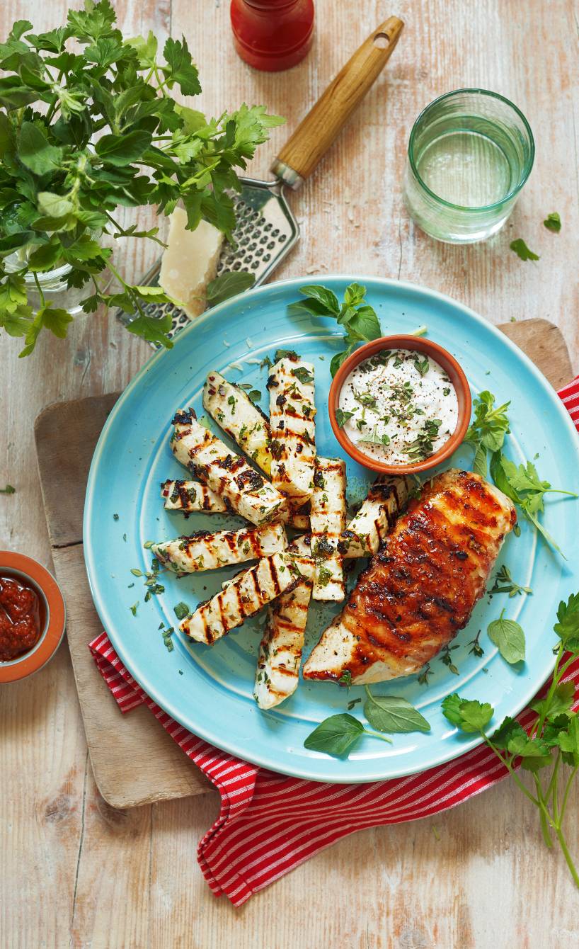 Gegrilltes Hähnchenbrustfilet im Pancettamantel auf einem Teller, daneben gegrillter Knollensellerie und Parmesandip