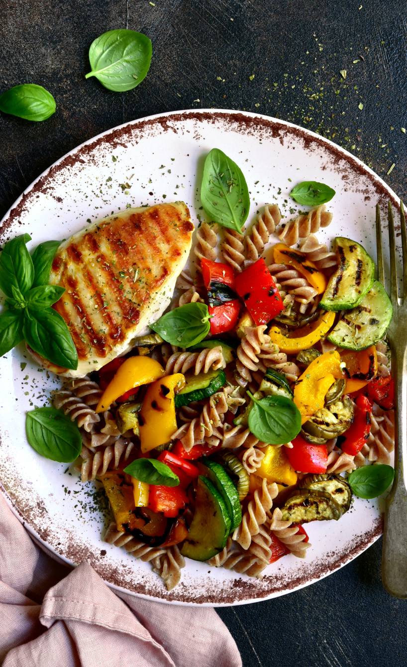 Vollkornnudeln, Gemüse und Hähnchenbrust angerichtet auf einem Teller