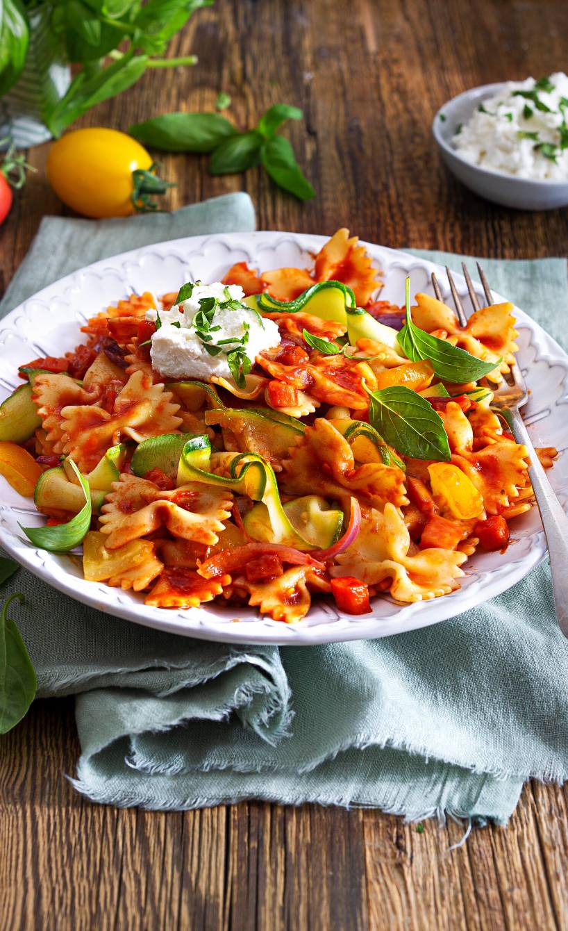 Gemüsenudeln in einem tiefen Teller getoppt von Ricottaflocken