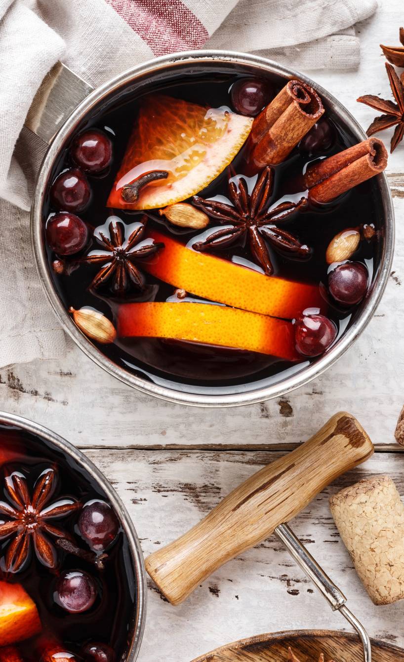 Selbst gemachter Glühwein in einem Topf, darin Blutorangenscheiben, Gewürze und Cranberries