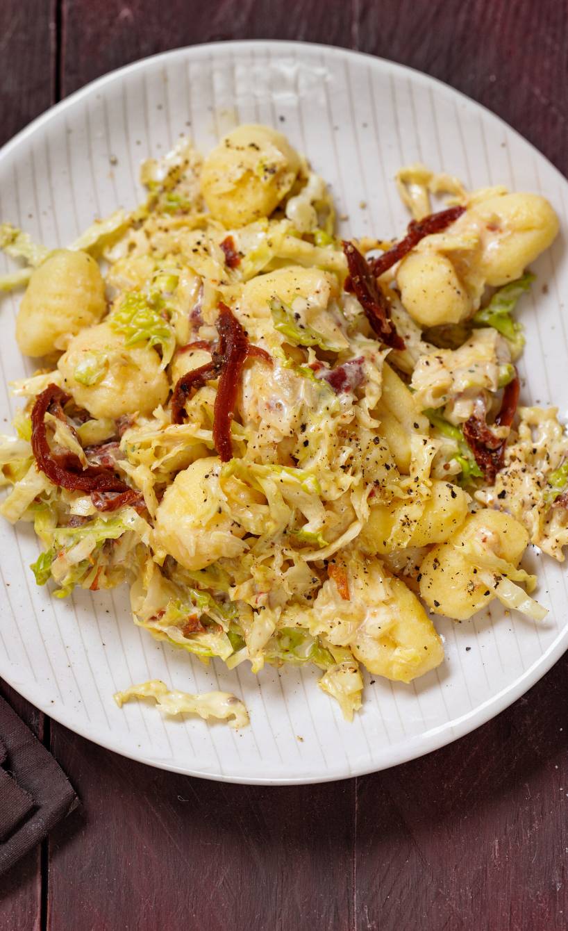 Gnocchi auf einem Teller, darauf mit Wirsinggemüse und Senfsauce