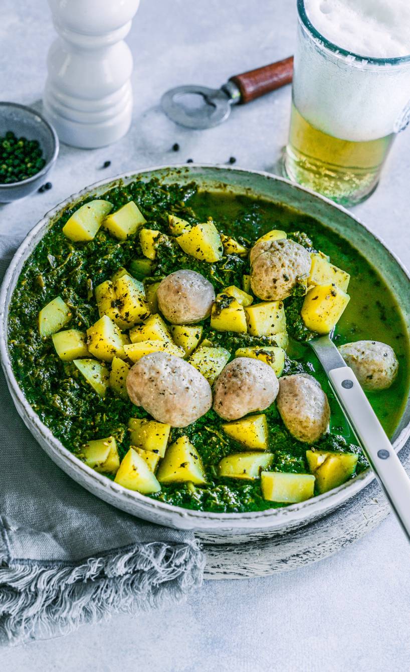 Italienischer Grünkohleintopf mit Kartoffeln und Speck getoppt von Salsiccia-Bällchen auf einem tiefen Teller