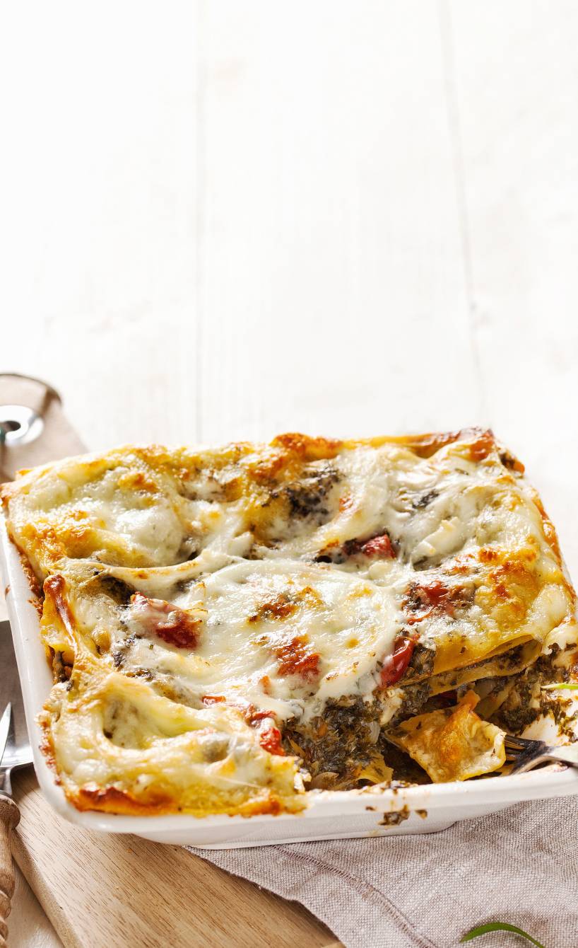 vegetarische Grünkohllasagne angeschnitten in einer viereckigen Auflaufform auf einem Tisch