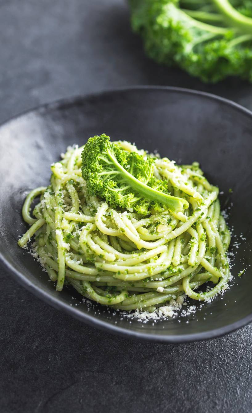 Spaghetti mit aromatischem Grünkohlpesto auf einem tiefen Teller bestreut mit Parmesan
