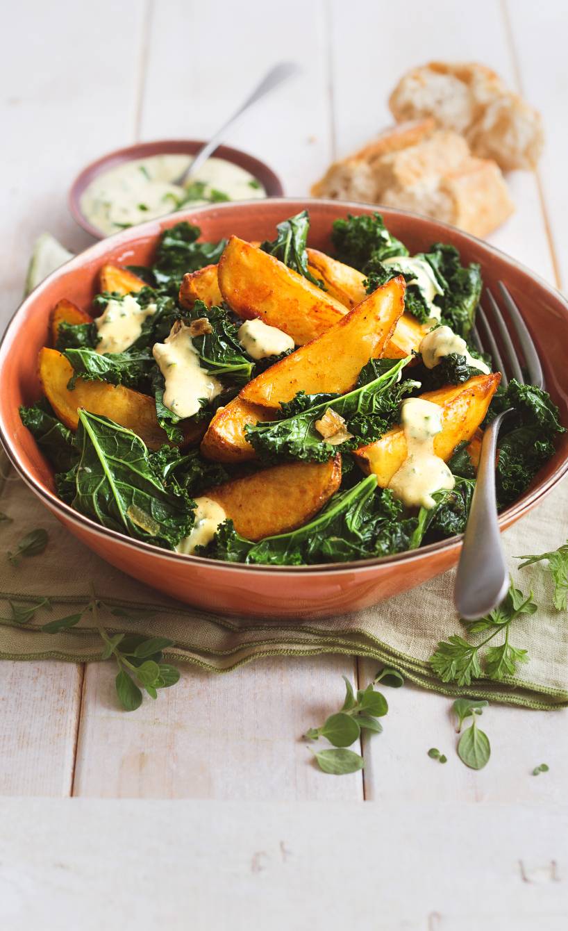 Grünkohlsalat getoppt mit Kartoffelspalten und Joghurt-Senf-Dressing in einem tiefen Teller