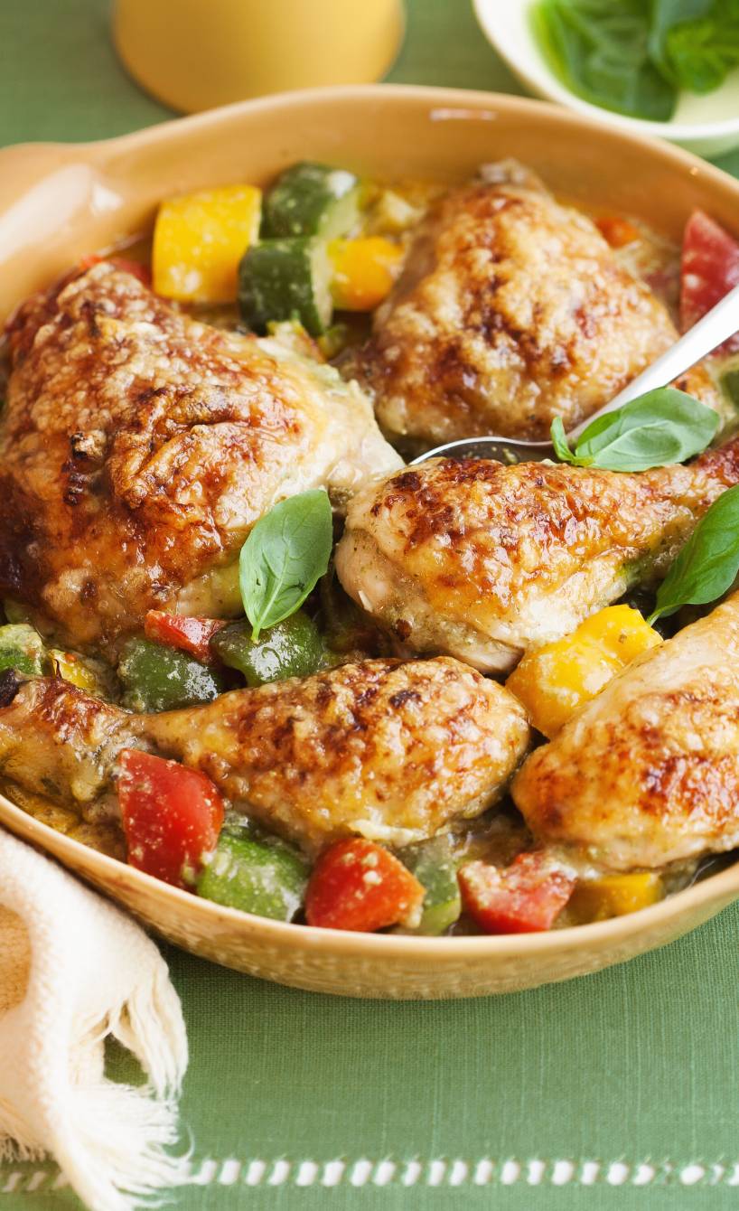 Gebackene Hähnchenkeulen mit Käsekruste auf italienischem Gemüse in einer Auflaufform