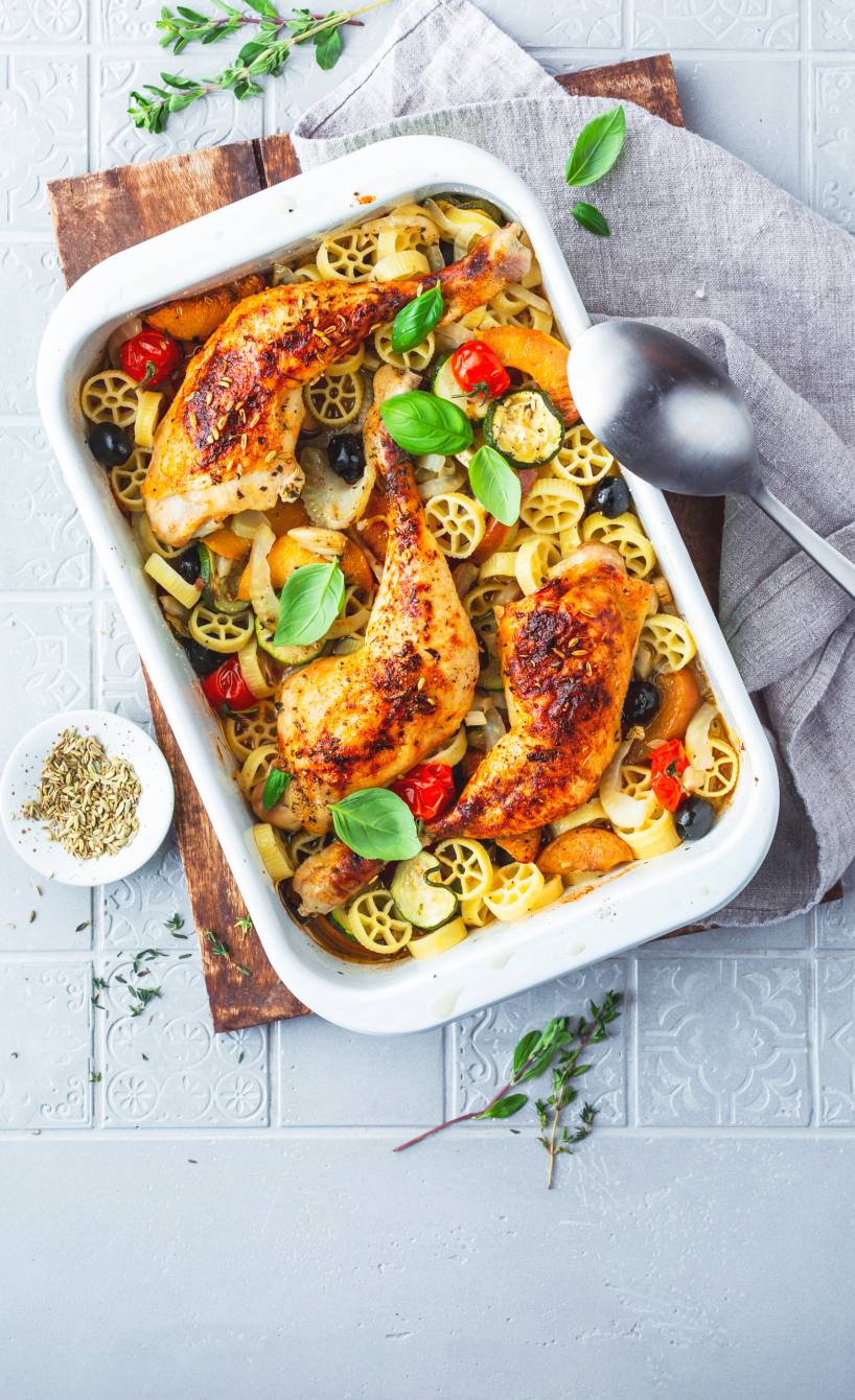 Gebackene Hähnchenkeulen auf Gemüsemix und Pfirsichen mit Rotelle-Nudeln in einer Auflaufform