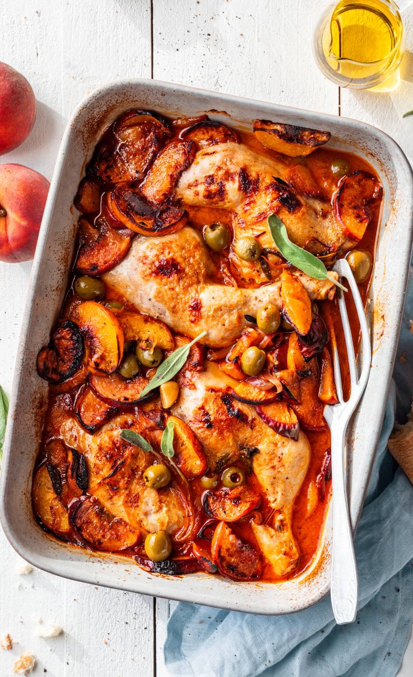 Gebackene Hähnchenschenkel mit Pfirsichen, Soße und Oliven in einer Auflaufform