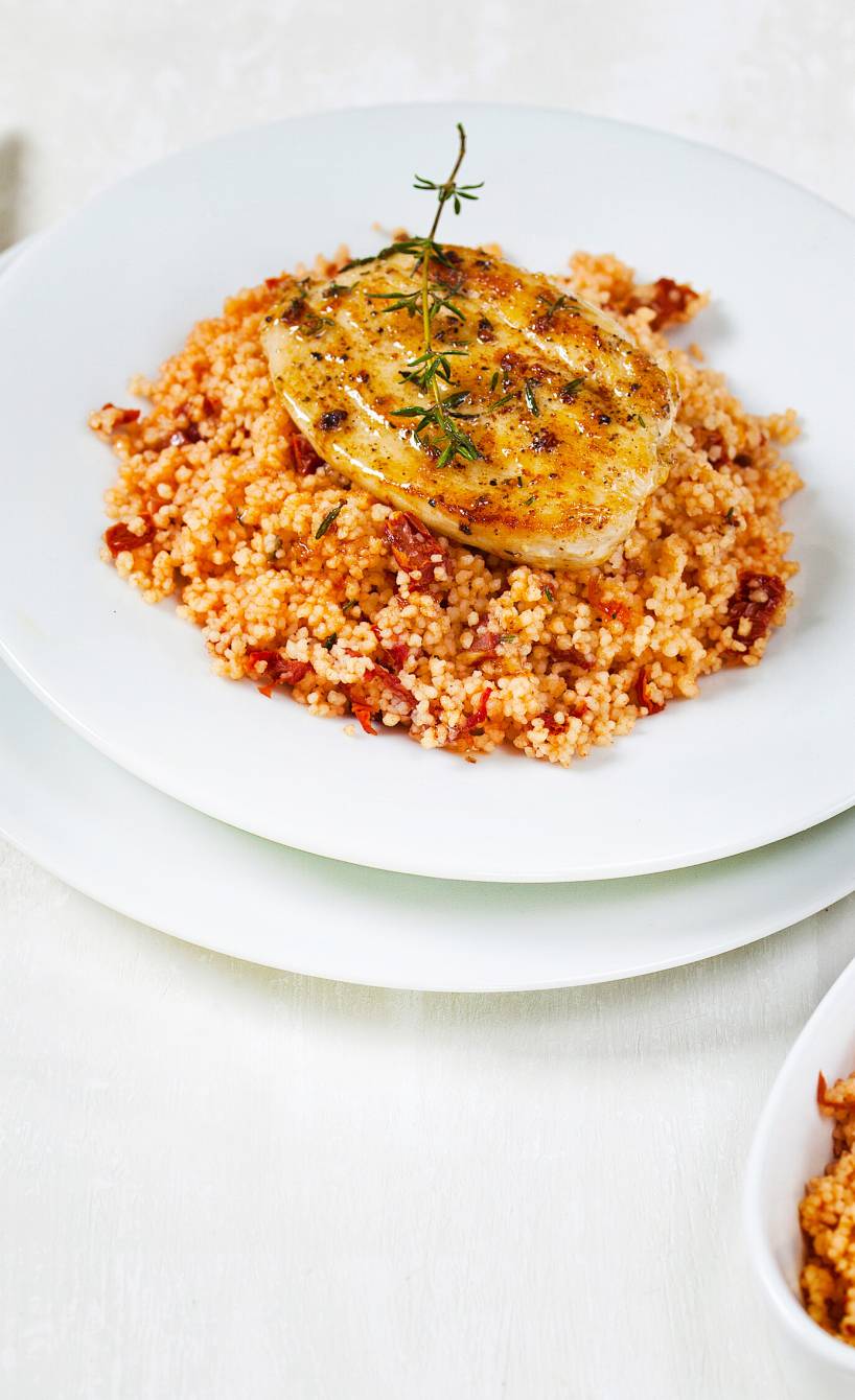 Gebratenes Hähnchen-Minutenschnitzel auf Tomaten-Couscous angerichtet auf einem tiefen Teller