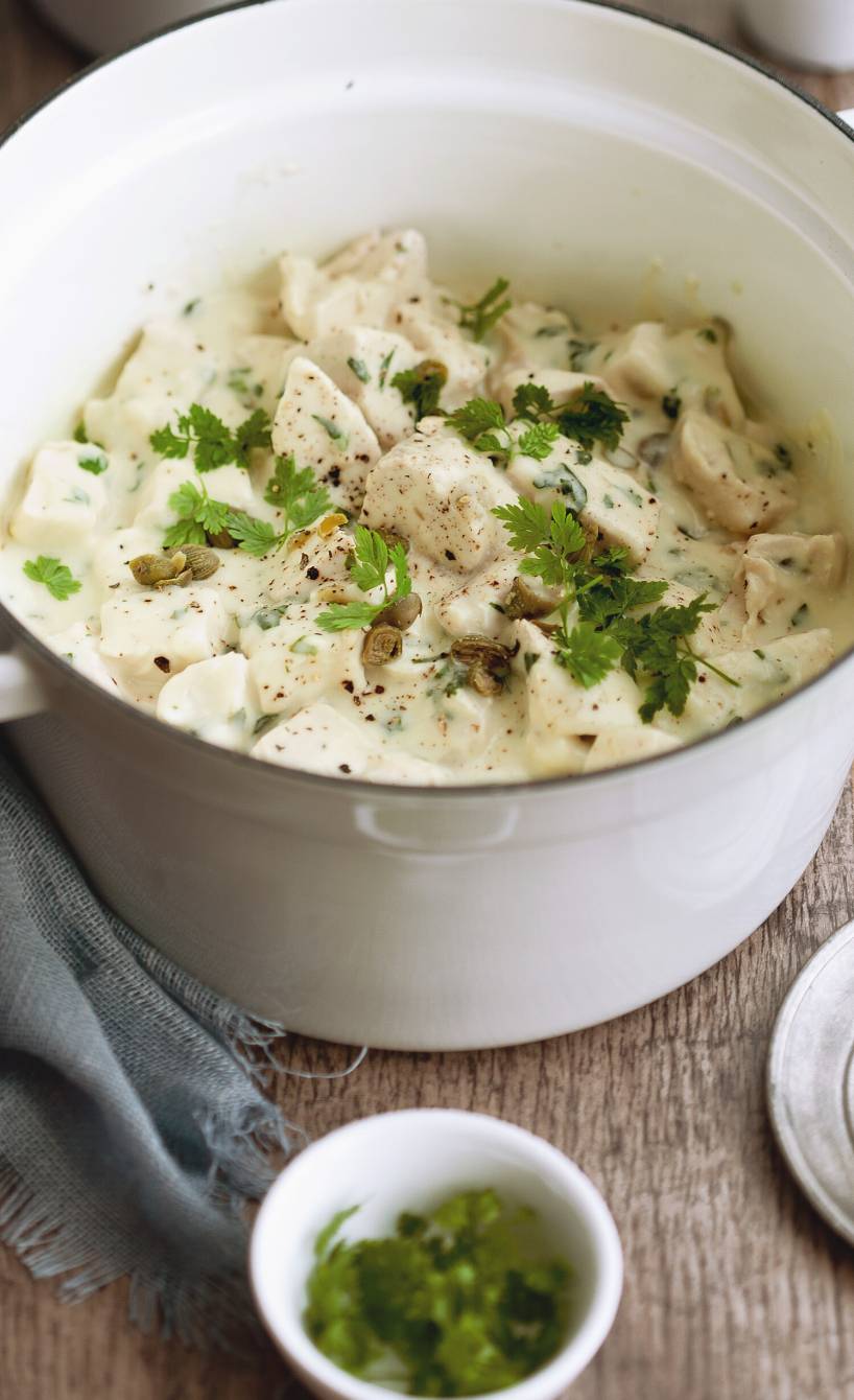 Hähnchenragout in Sahnesauce in einem Topf auf einem Holztisch