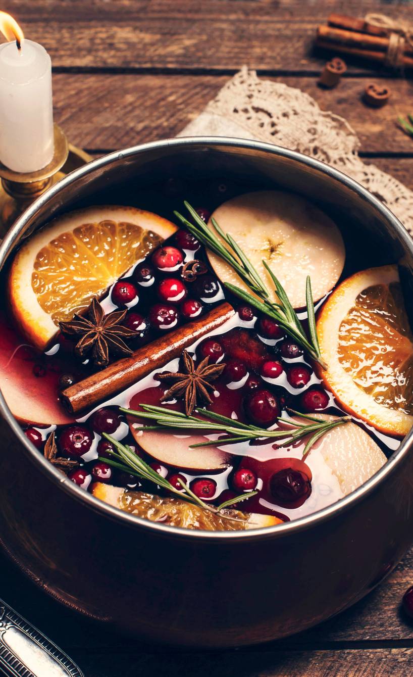 Selbst gemachter Früchtepunsch in einem Topf auf einem Holztisch mit Kerzen