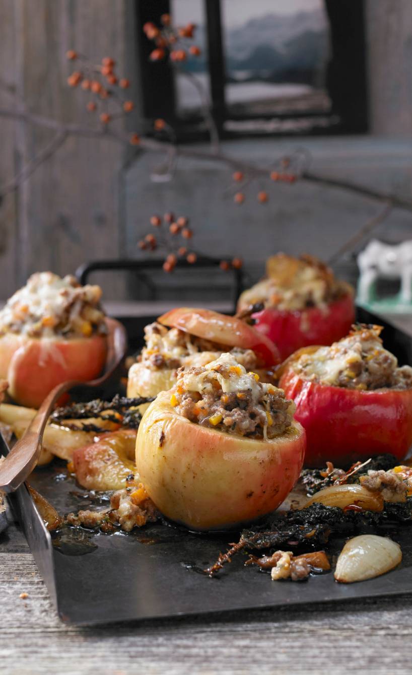 Fünf Bratäpfel auf einem Backblech mit Hackfleischfüllung und Käse überbacken