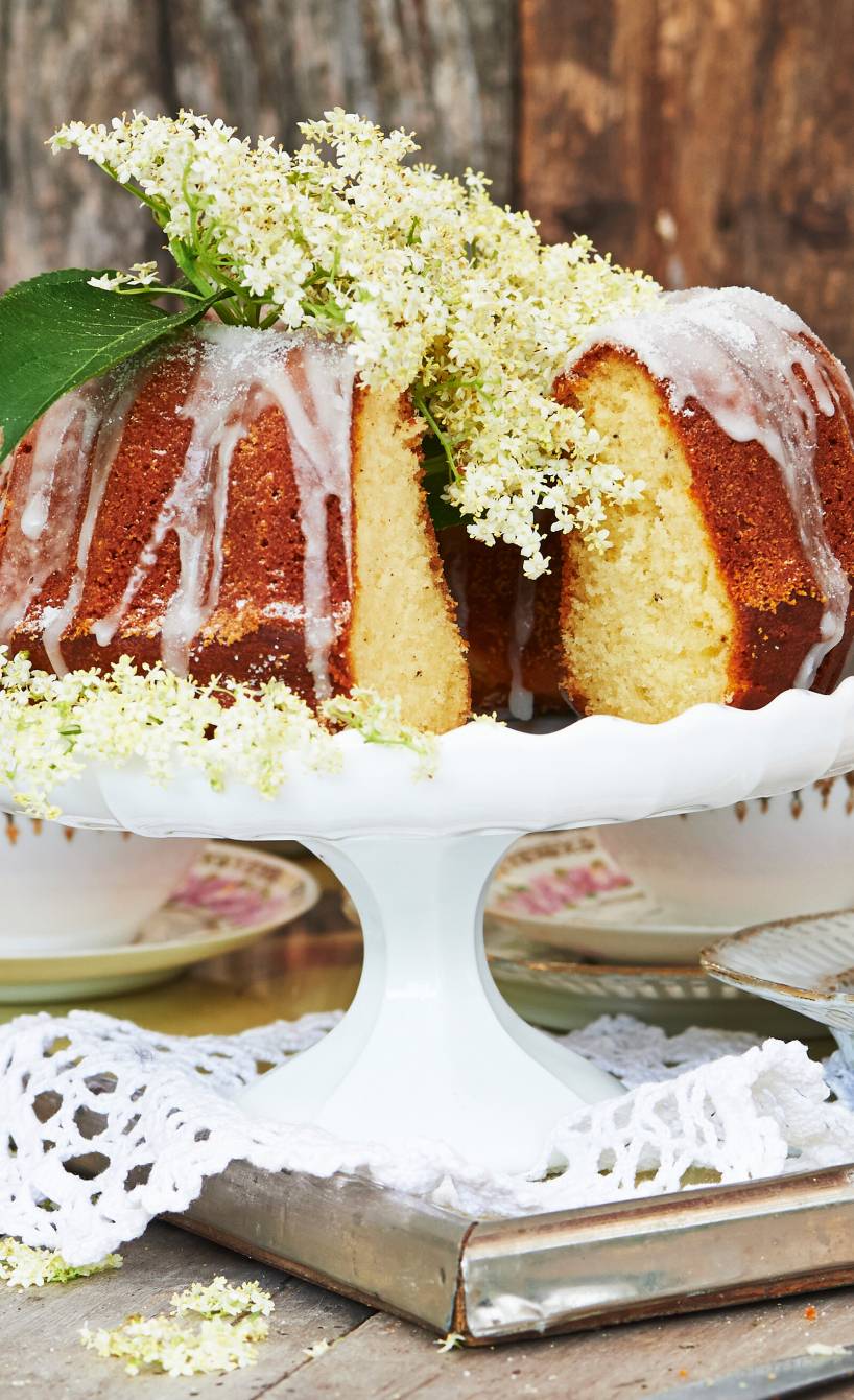 Gugelhupf mit Joghurt, Holunderblütensirup und Zitrone angeschnitten auf einer Tortenplatte