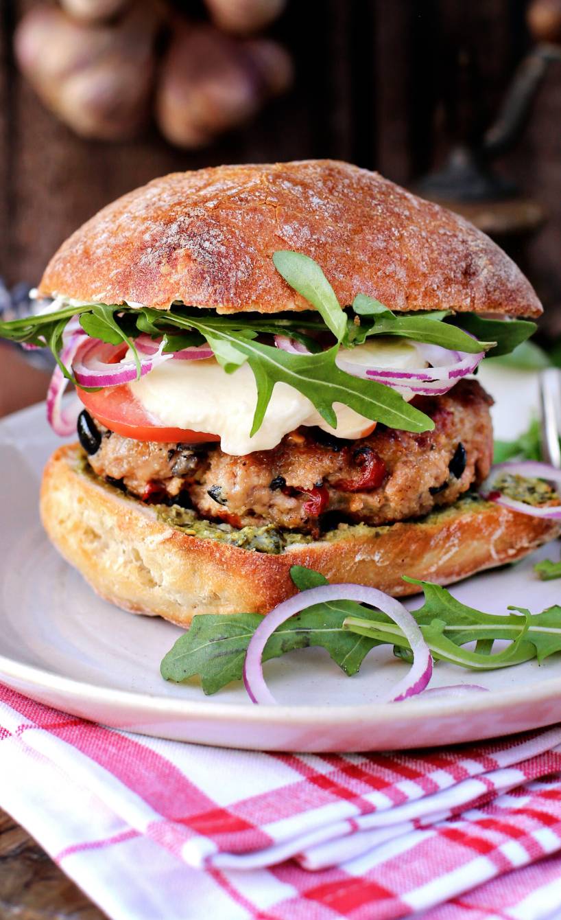 Italienischer Burger auf einem Teller, Patty, Mozzarella und Rucola erkennbar