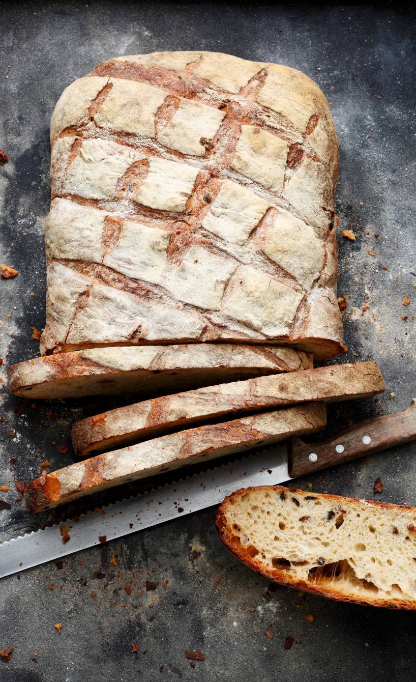 Brotlaib angeschnitten auf einem Tisch, daneben ein Brotmesser