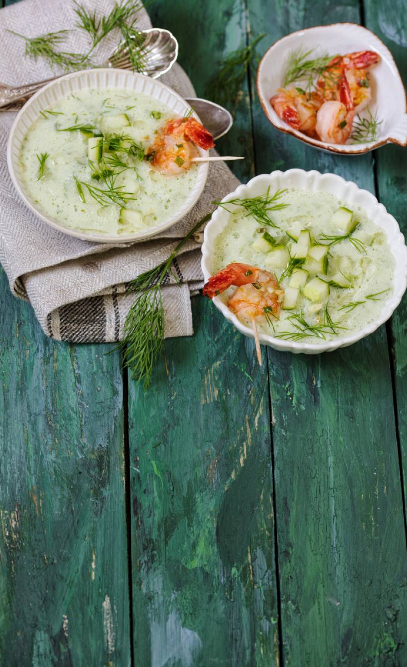 Gurkensuppe in mehreren Schüsseln getoppt mit gebratenen Garnelen und Dill auf einem Tisch