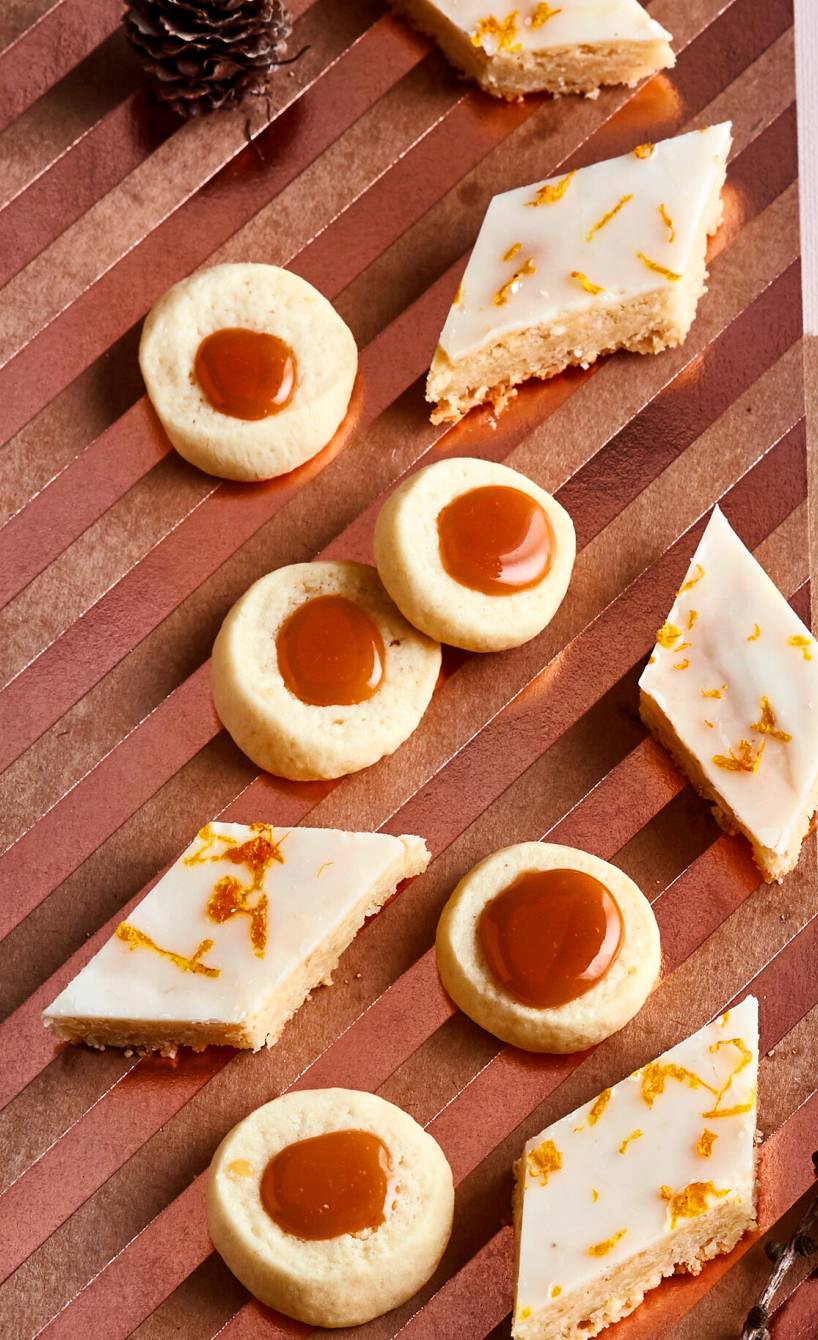 Runde Karamellkekse und rautenförmige Weihnachtsplätzchen auf einem Holzbrett