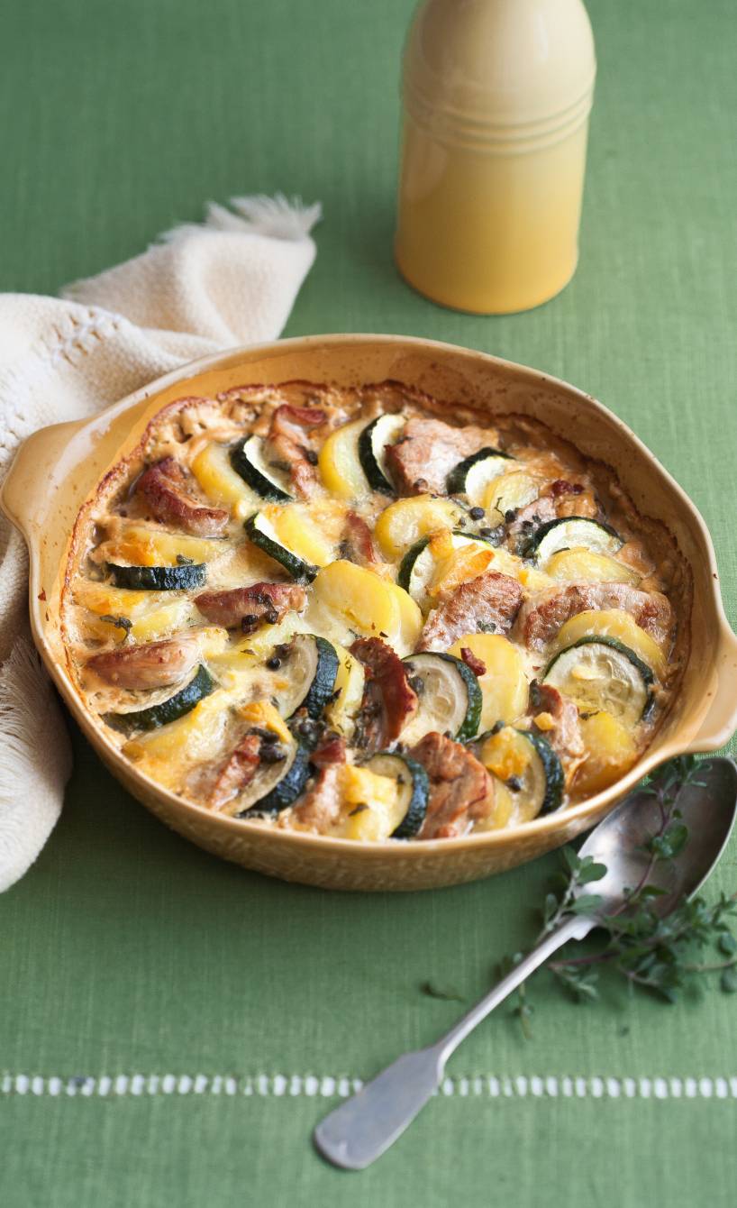 Zucchini-Kartoffelgratin mit Schweinefilet mit Käse überbacken in einer runden Auflaufform