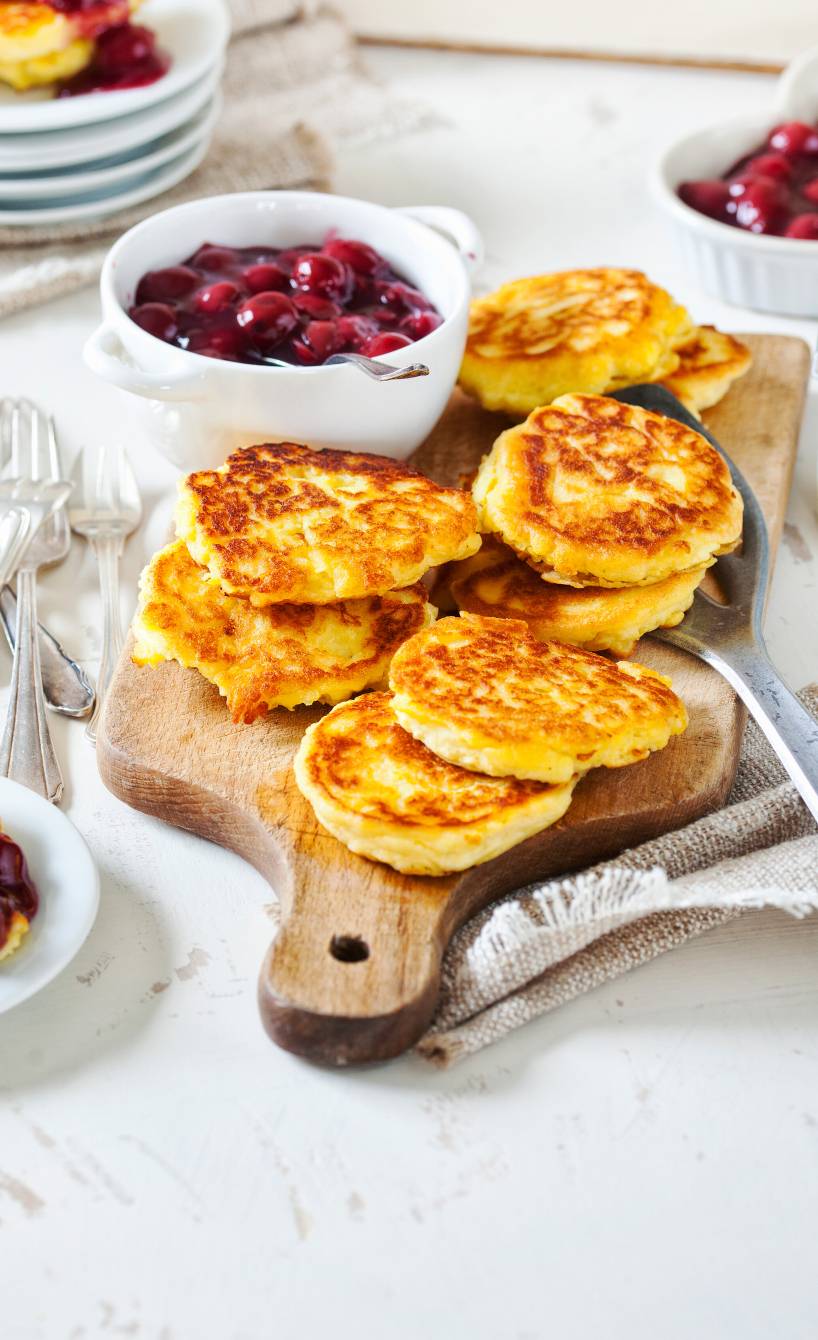 Mehrere gebratene Kartoffelküchlein auf einem Holzbrett, daneben mit Glühwein-Kirschen-Sauce in einer Schale