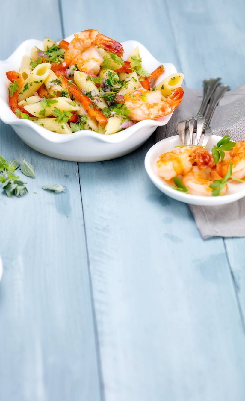 Nudelsalat getoppt mit Garnelen in einer Salatschüssel auf einem Tisch