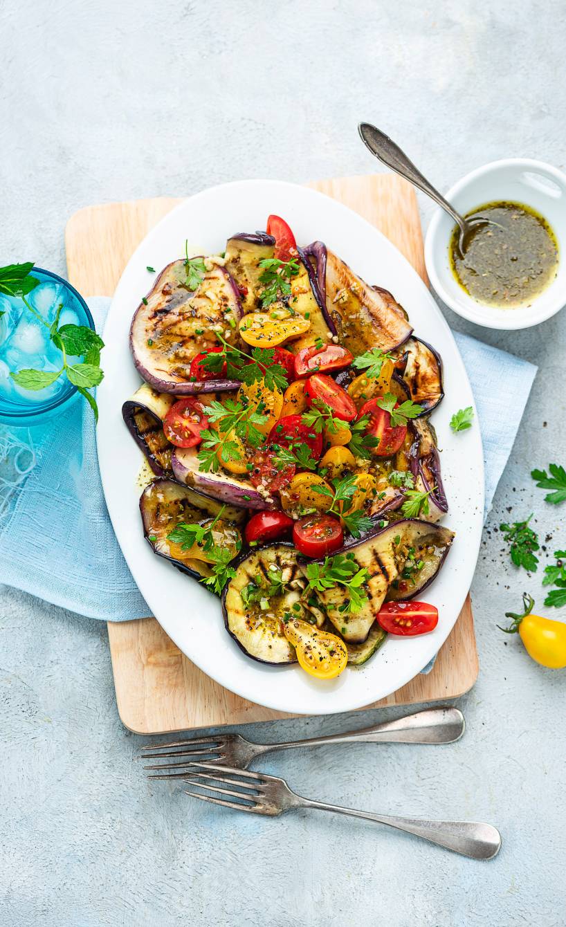 Grillgemüse auf einem ovalen Teller, daneben eine Schüssel mit Marinade