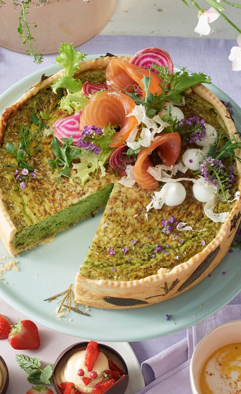 Kräuterquiche angeschnitten auf einem österlich dekorierten Tisch getoppt mit Räucherlachs und Dill