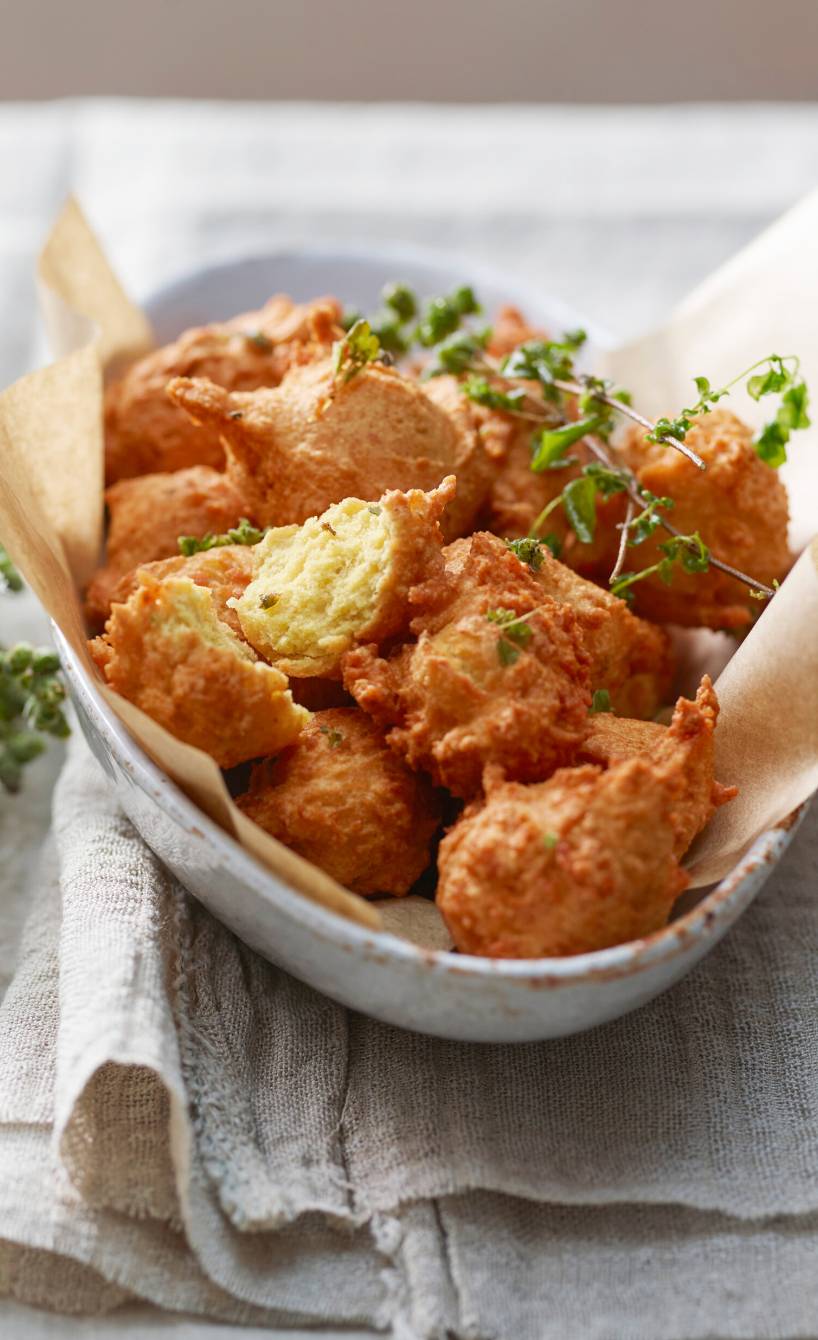 Frittierte Kichererbsenbällchen in einer Schale getoppt mit frischen Kräutern, daneben ein Dip