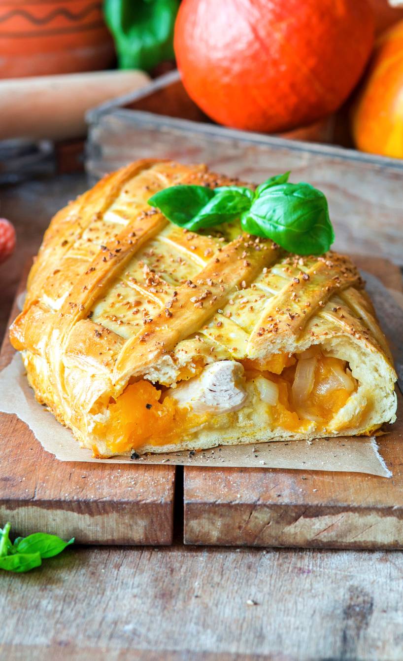 Kürbisstrudel mit Hähnchen gefüllt angeschnitten auf einem Holzbrett