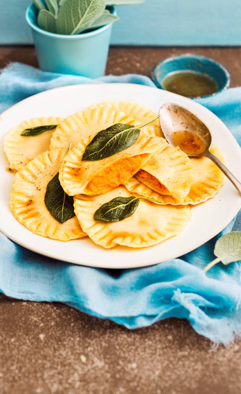 Ravioli auf einem Teller, einige halbiert, sodass die Kürbisfüllung sichtbar ist