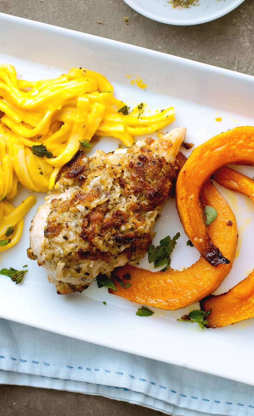 Tagliatelle mit Kürbissoße und Kürbisspalten und Hähnchenbrustfilet auf einem Teller