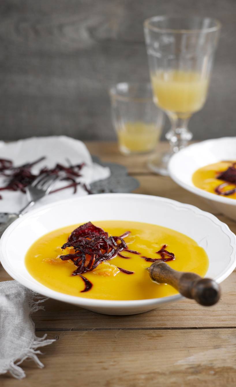 Selbstgekochte Kürbissuppe angerichtet auf zwei Supentellern mit frittierten Rote-Bete-Streifen