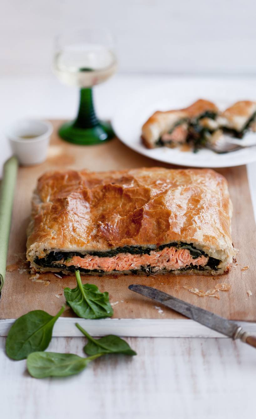 Lachs und Spinat im Blätterteigmantel angeschnitten auf einem Holzbrett